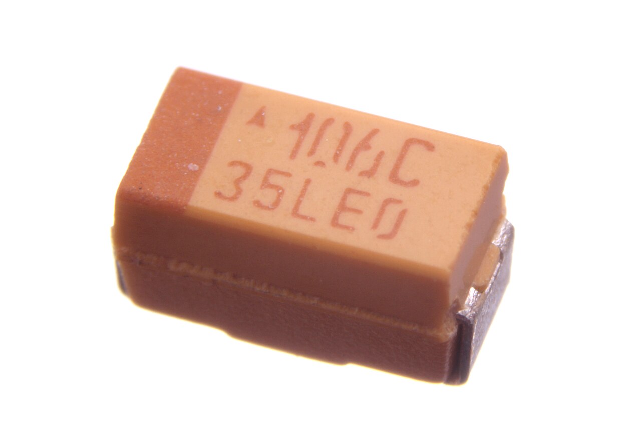 Figure 5 — Molded SMD tantalum chips. The dark bar marks the POSITIVE terminal — the reverse of the aluminum-electrolytic convention, and a classic wiring trap. Source: Wikimedia Commons, oomlout (…