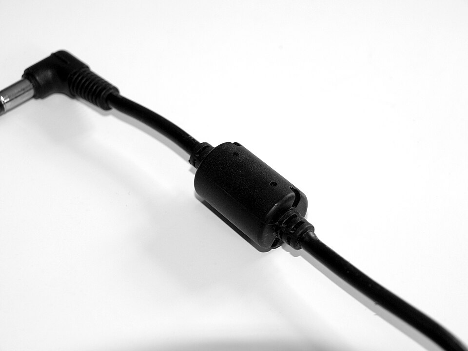 Figure 9 — A ferrite bead: a short NiZn ferrite sleeve over a conductor, a deliberately lossy one-turn inductor for suppressing high-frequency interference. Source: Wikimedia Commons (Santeri Viina…
