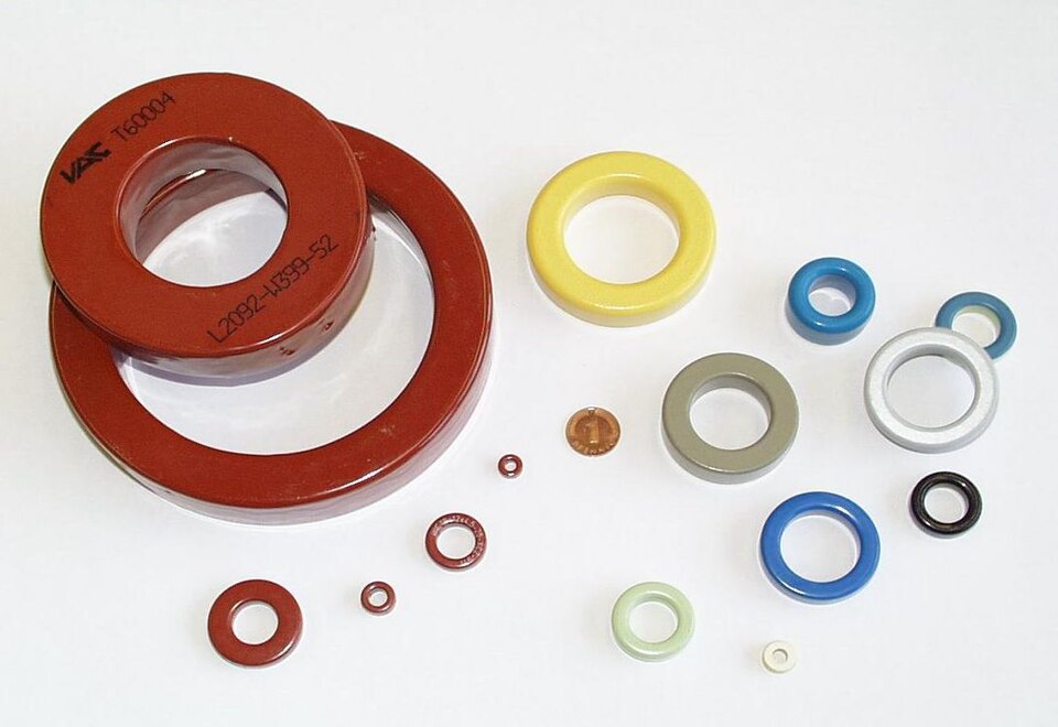 Figure 6 — Assorted iron-powder and ferrite toroidal cores. Iron-powder mixes are colour-coded to identify the material and its permeability. Source: Wikimedia Commons (Harry20), CC BY-SA 3.0.