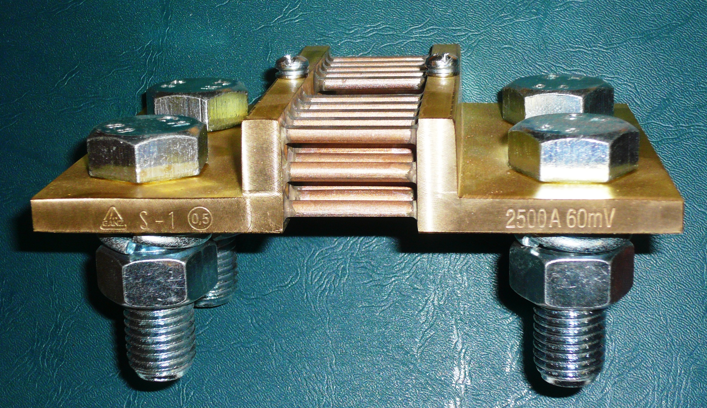 Figure 2 — A real four-terminal current shunt, rated 2500 A / 60 mV, accuracy class 0.5. The two large outer bolts are the FORCE terminals that carry the 2500 A load current; the two small screw te…
