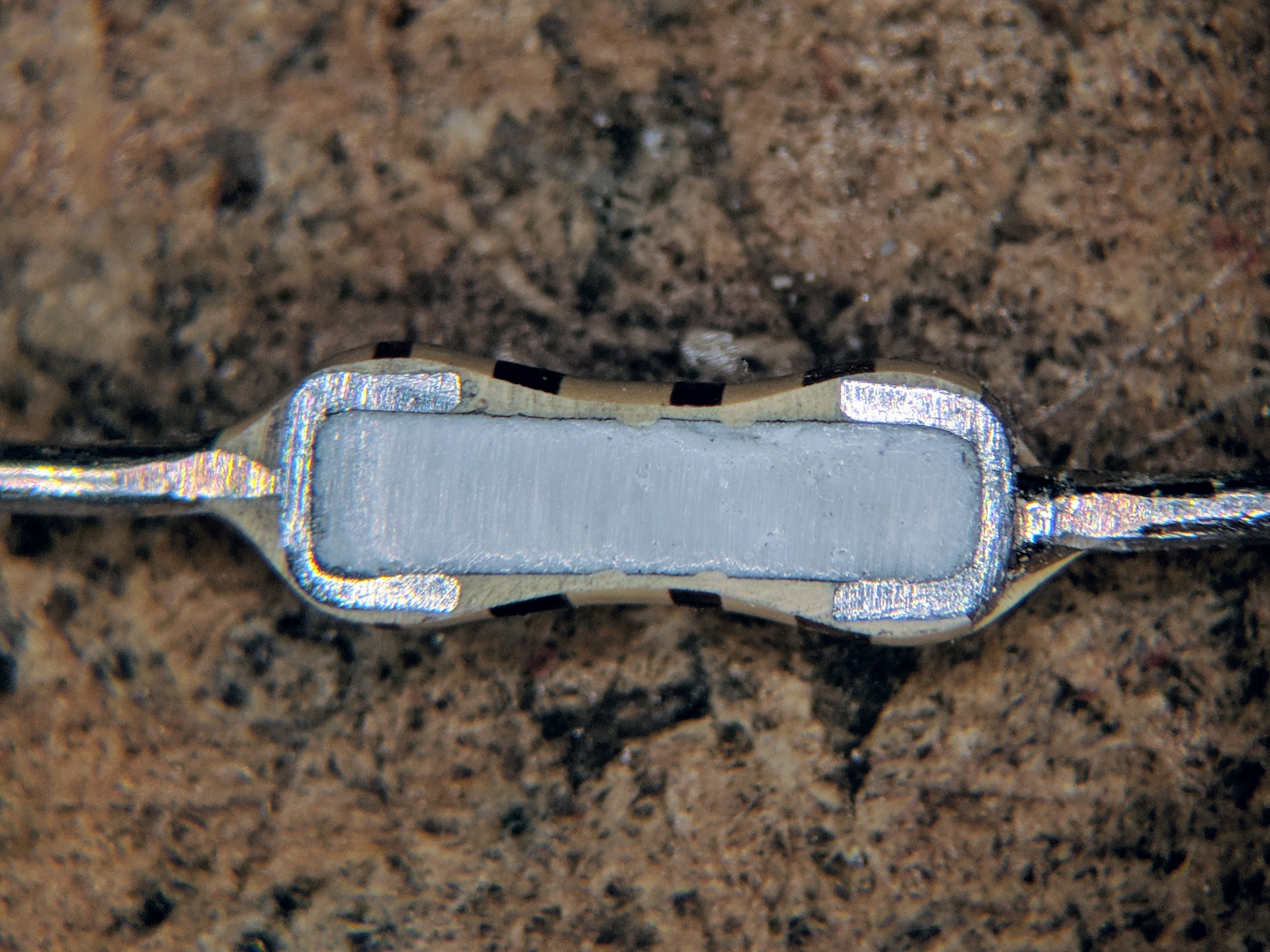 Figure 5 — Cross-section of a common quarter-watt axial carbon-film resistor. The spiral groove cut through the dark film is the helix that sets the value — and the source of the part's parasitic s…