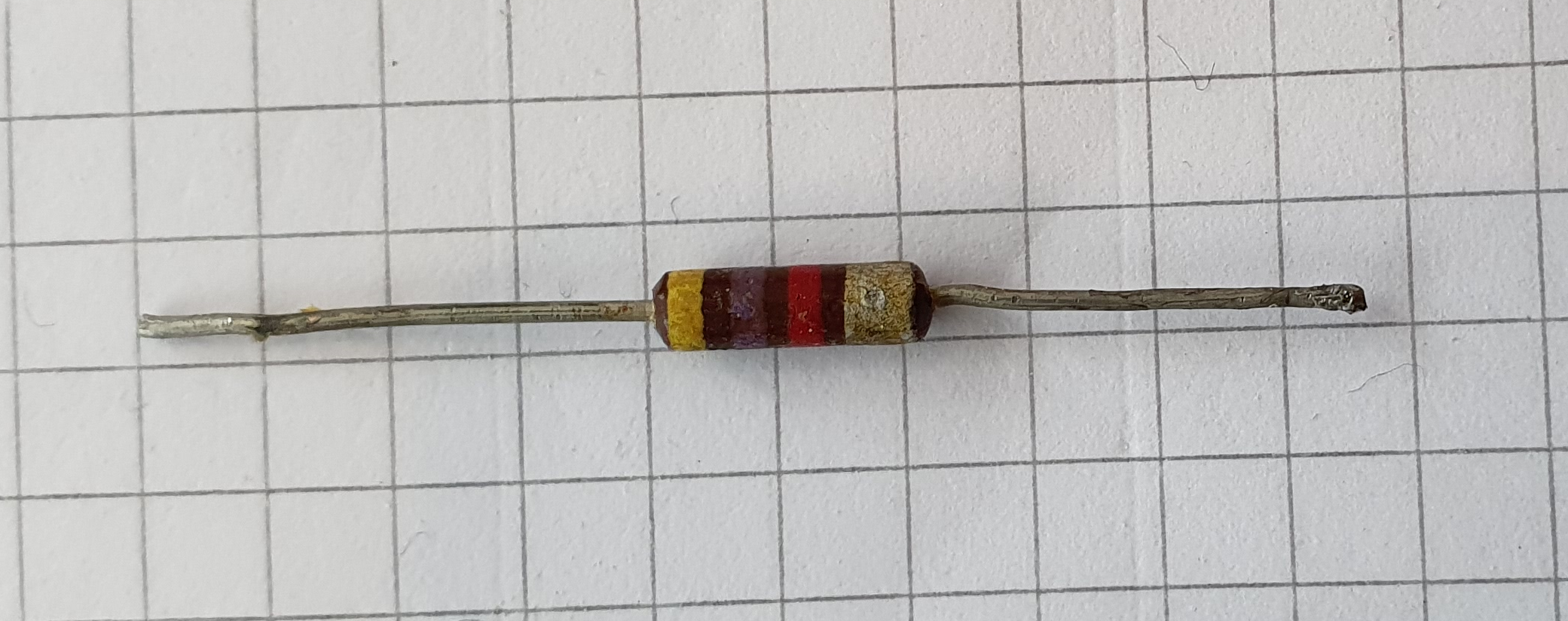 Figure 2 — A real carbon-composition resistor (4.7 kΩ, ±10%), the molded cylindrical body typical of the tube and early transistor era. The color bands are painted on a phenolic coat over the molde…