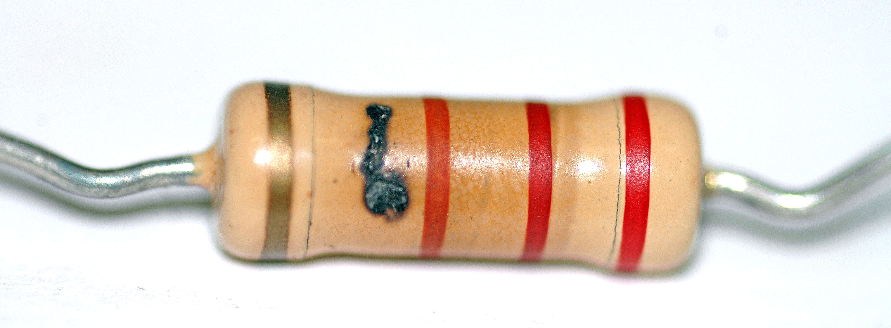 Figure 8 — A charred carbon-film resistor. The dark blistered patch over the element is where the coating and body burned under overload — the visible fingerprint of a resistor pushed far past its …