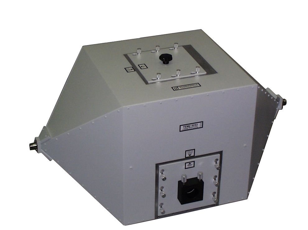 Figure 9 — A TEM cell, a shielded transverse-electromagnetic test enclosure at bench scale. Between the honeycomb-vented professional room and the fabric-tent hobby shield sits a family of small, w…