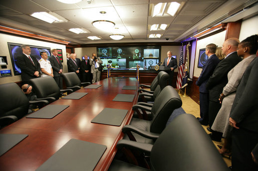 Figure 3 — President Bush at the May 2007 ribbon-cutting for the newly renovated Situation Room. The wood panelling is a finish over a hardened, windowless, shielded shell; the wall of flat panels …
