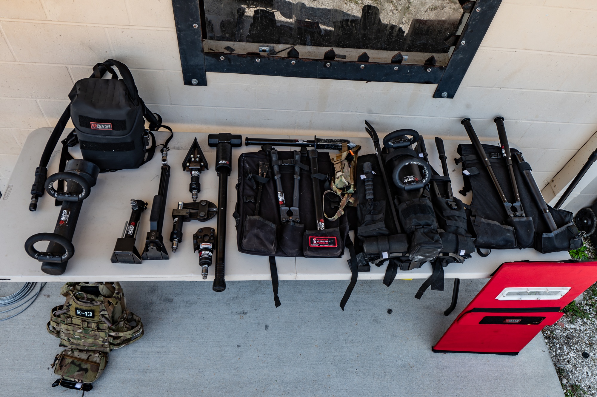 Figure 7 — Figure G — The purpose-built SCIF-door breaching kit developed by the 6th Security Forces Squadron with a breaching-equipment company: hydraulic rams, a hinge puller, spreaders, and cutters, laid o…