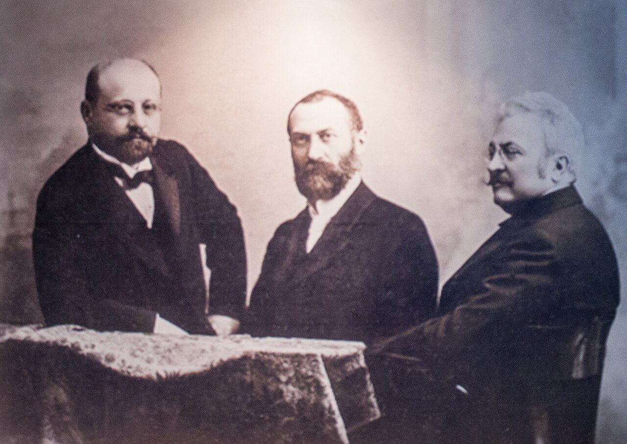 Figure 4 — The ZBD team at the Ganz Works in Budapest: Miksa Déri, Ottó Bláthy and Károly Zipernowsky. Their 1885 closed-core transformer, connected in parallel for constant voltage, made practical…
