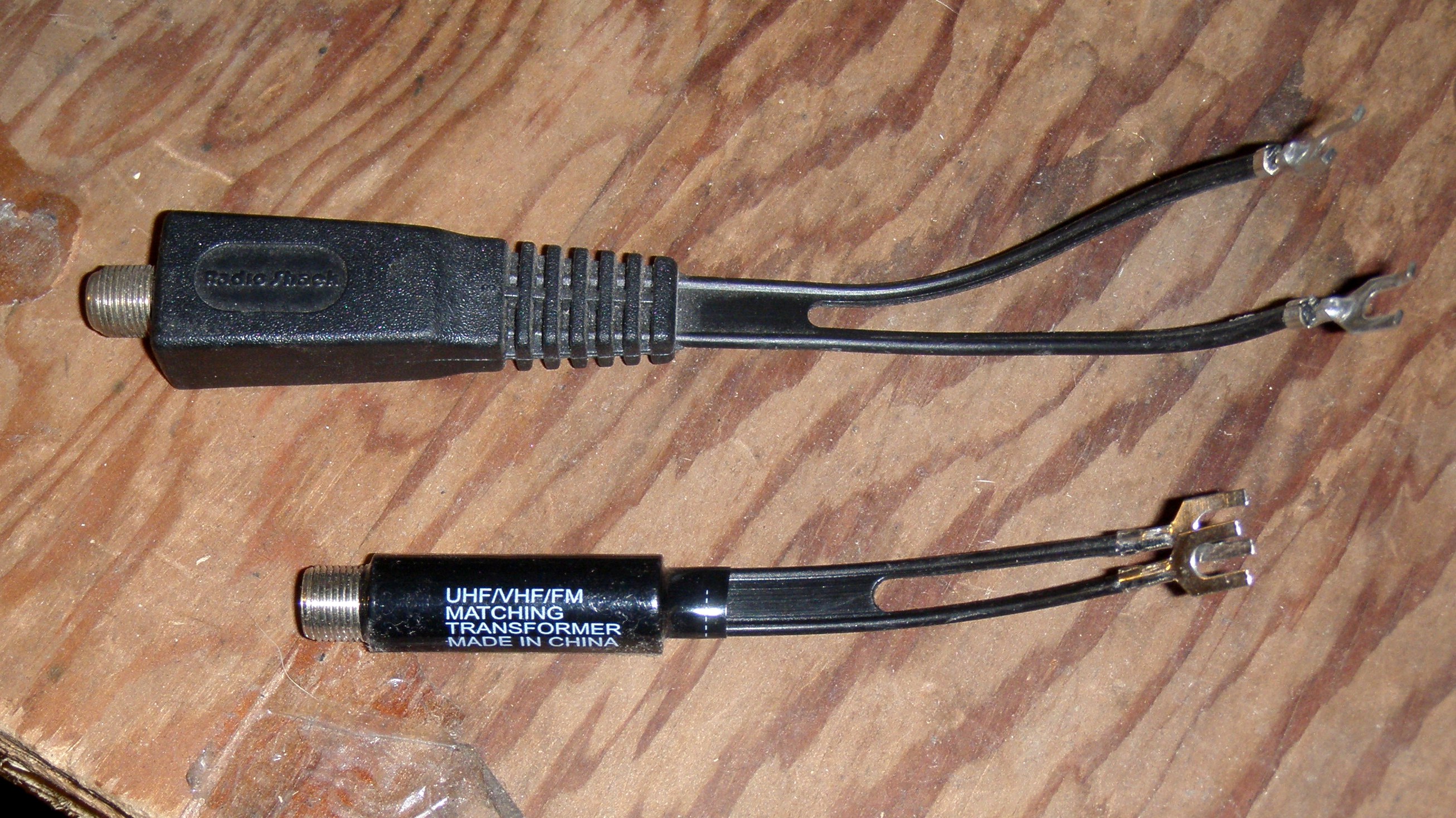 Figure 6 — Two commercial antenna matching transformers (baluns): a 300-ohm-to-75-ohm television balun (bottom, marked "UHF/VHF/FM MATCHING TRANSFORMER") and a similar unit above, each converting a…