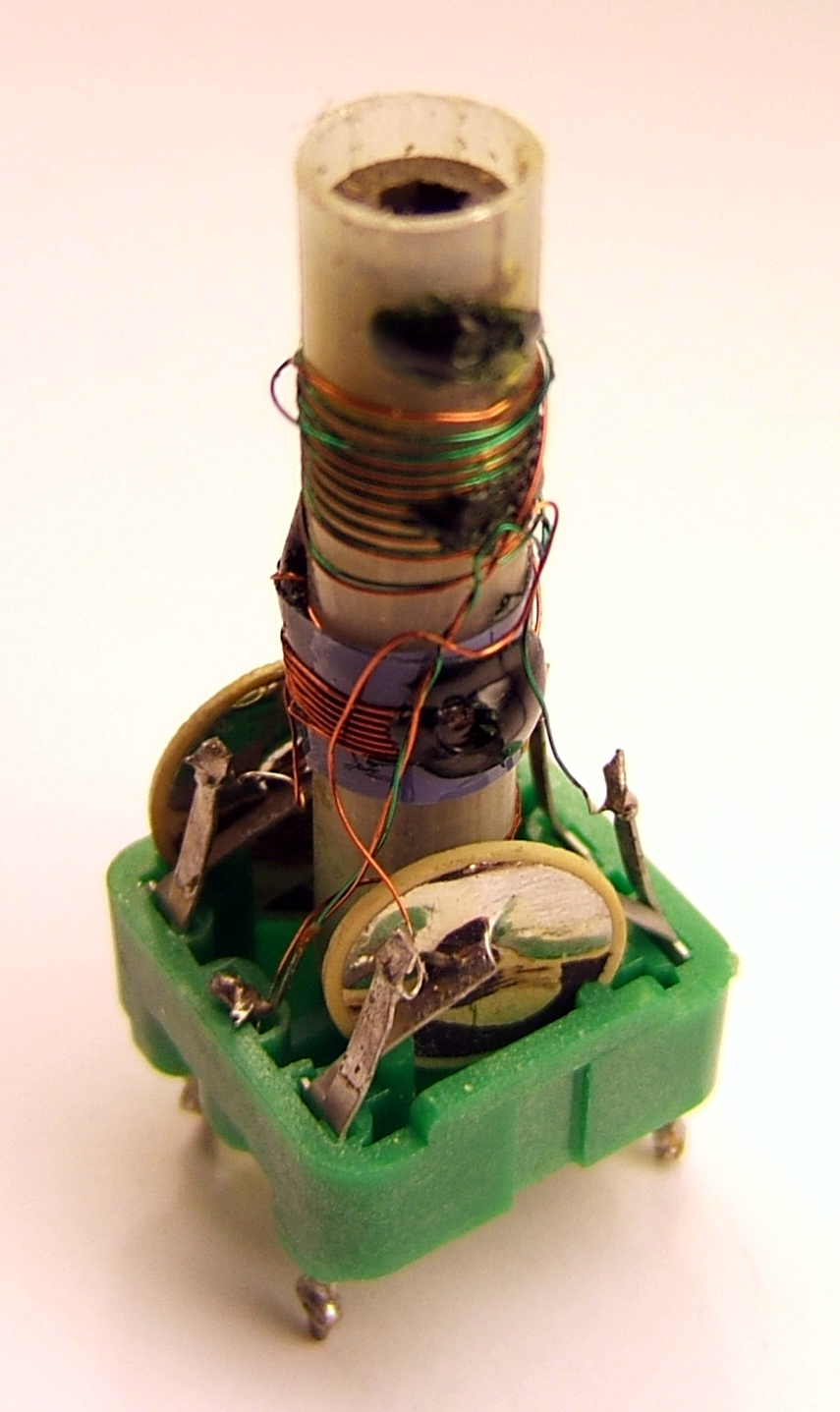Figure 3 — An IF transformer with its shield can removed, showing the two windings on the slug-tuned former and the resonating capacitors moulded into the base. The threaded ferrite slug moves insi…