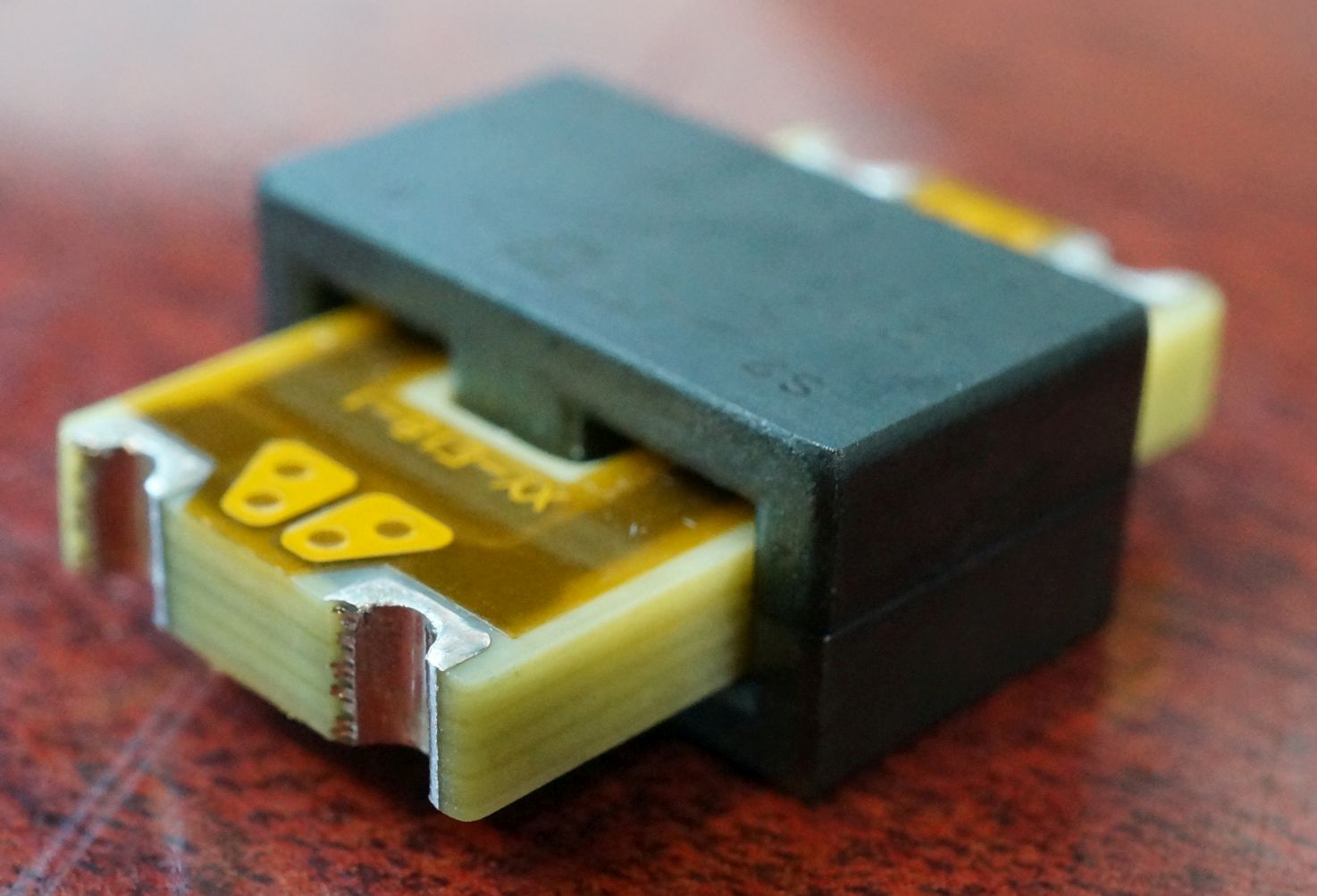 Figure 8 — A planar transformer: flat copper windings formed on a multilayer printed-circuit board are clamped between two halves of a low-profile ferrite core. The PCB windings give low, repeatabl…